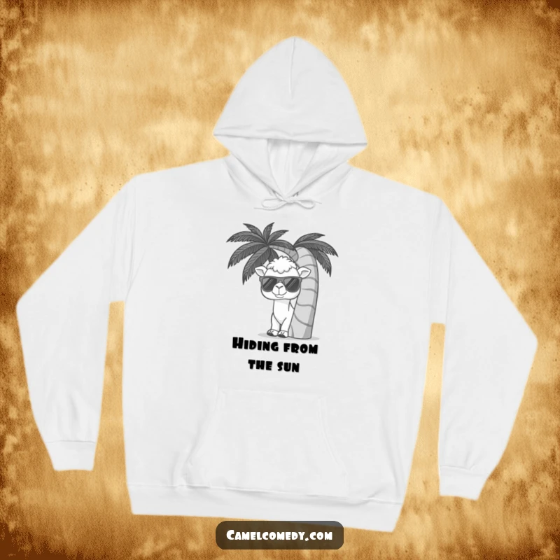 Funny hoodie with a kawaii camel wearing sunglasses, peeking from behind a palm tree, offering cozy tropical humor.