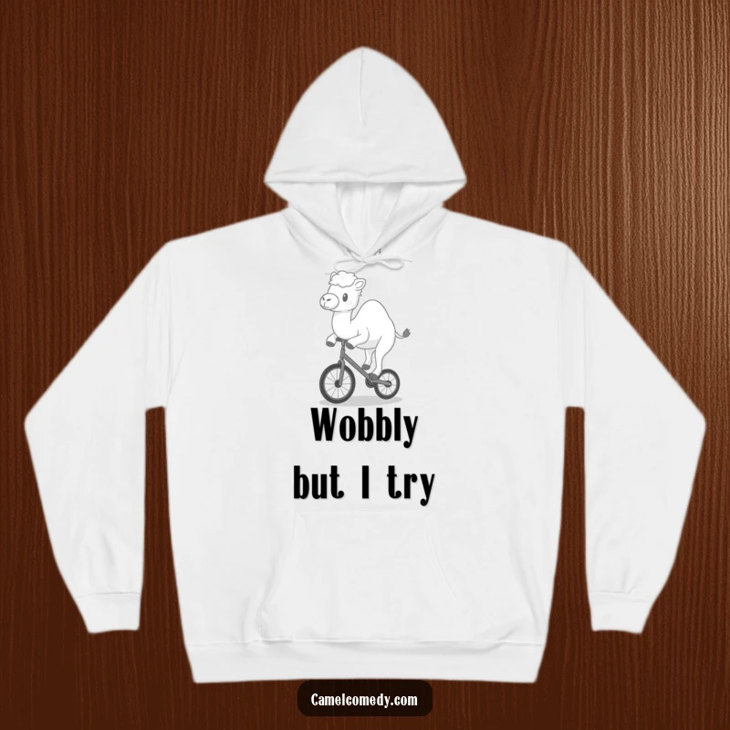 Funny hoodie with a kawaii camel happily wobbling on a tiny unicycle, offering cozy and humorous circus vibes.